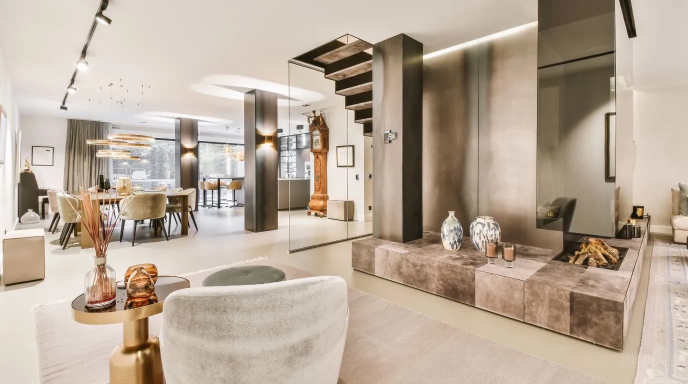 Open-plan living area with a stone fireplace block and a staircase behind glass
